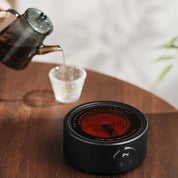 Elektrischer Kaffeewärmer auf einem Holztisch beim Eingießen von Kaffee