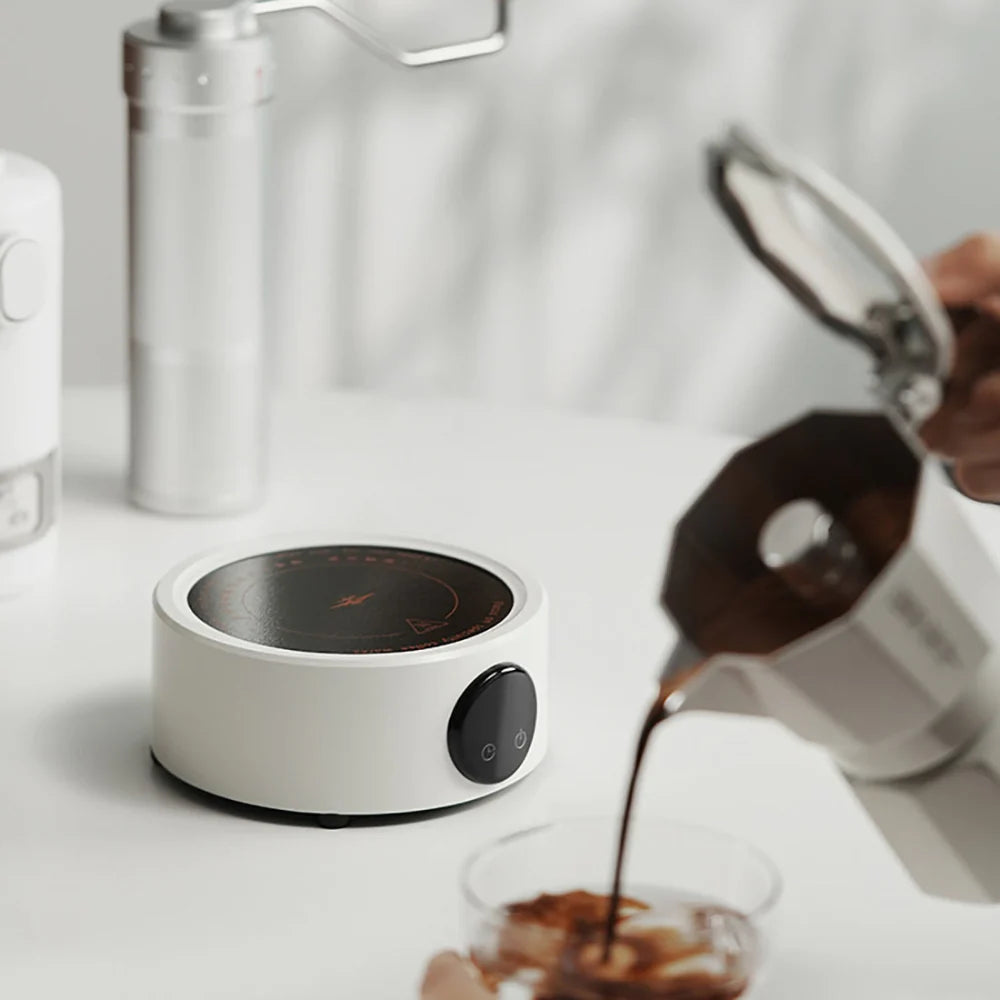 Elektrischer Kaffeewärmer in Weiß auf einem Tisch beim Einschenken von Kaffee