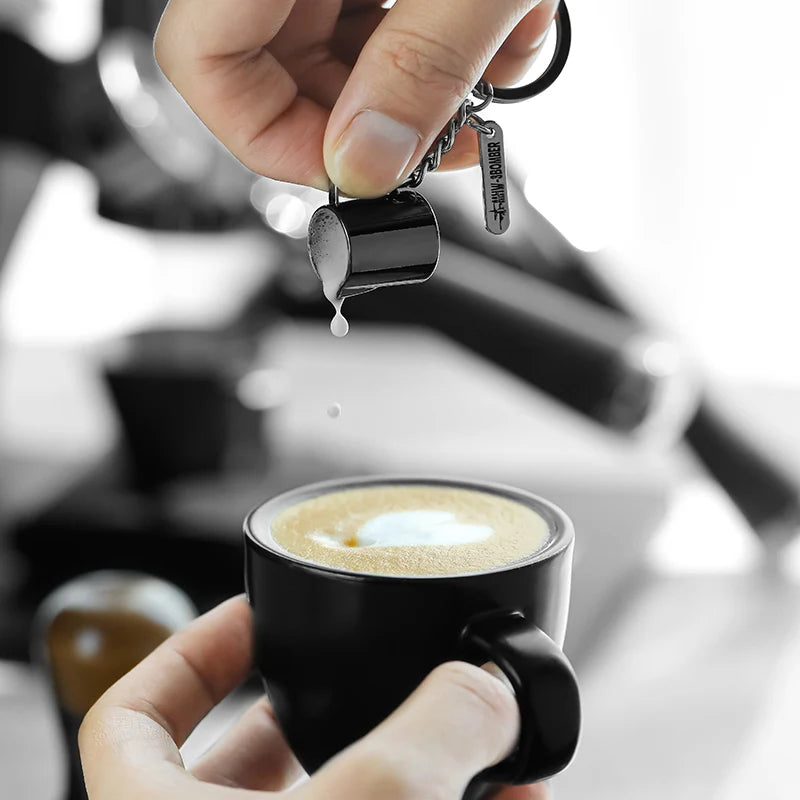 Milchkännchen-Schlüsselanhänger über einer Tasse Kaffee in einer Barista-Szene
